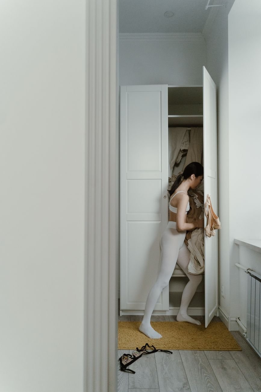 A woman sorts her clothing in a wardrobe, emphasizing home organization.